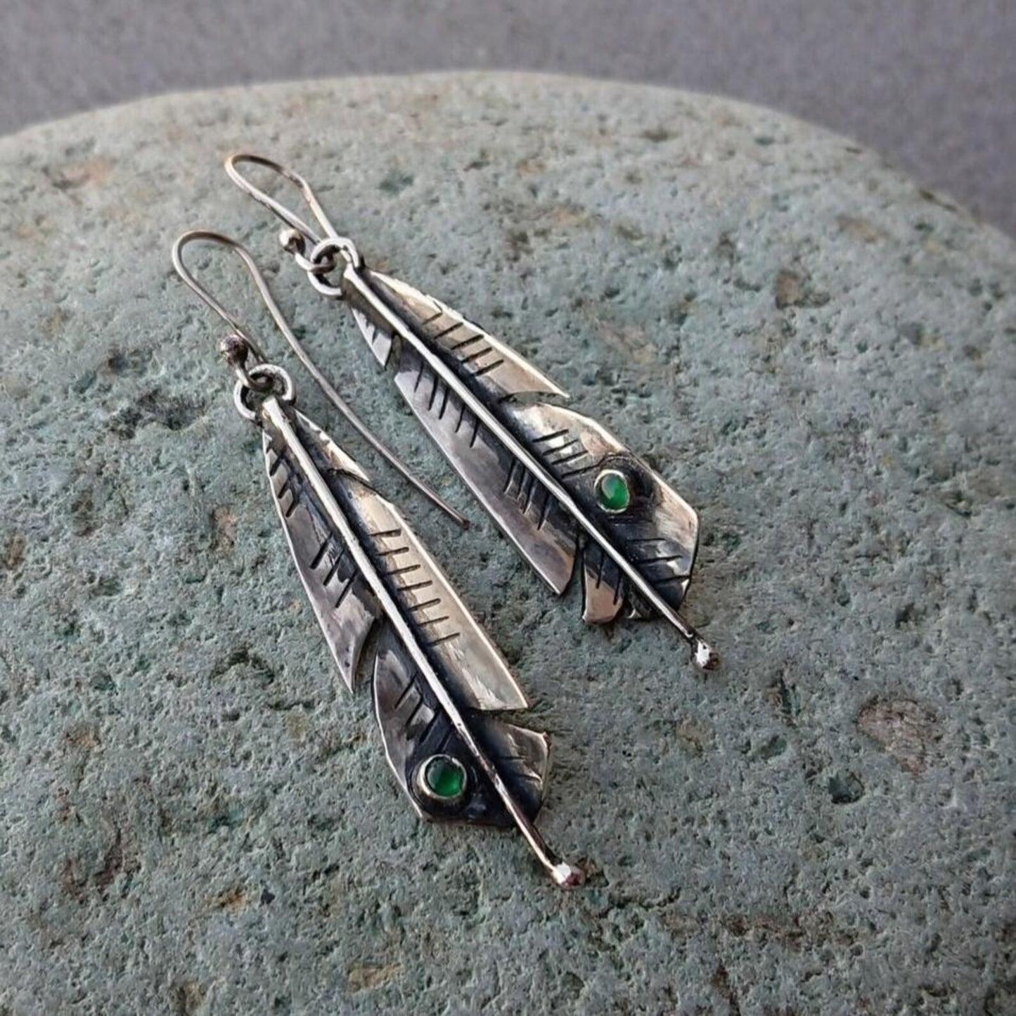 Handcrafted Armenian sterling silver artisan earrings shaped like detailed feathers, each set with small, vibrant round green onyx cabochon near the tip