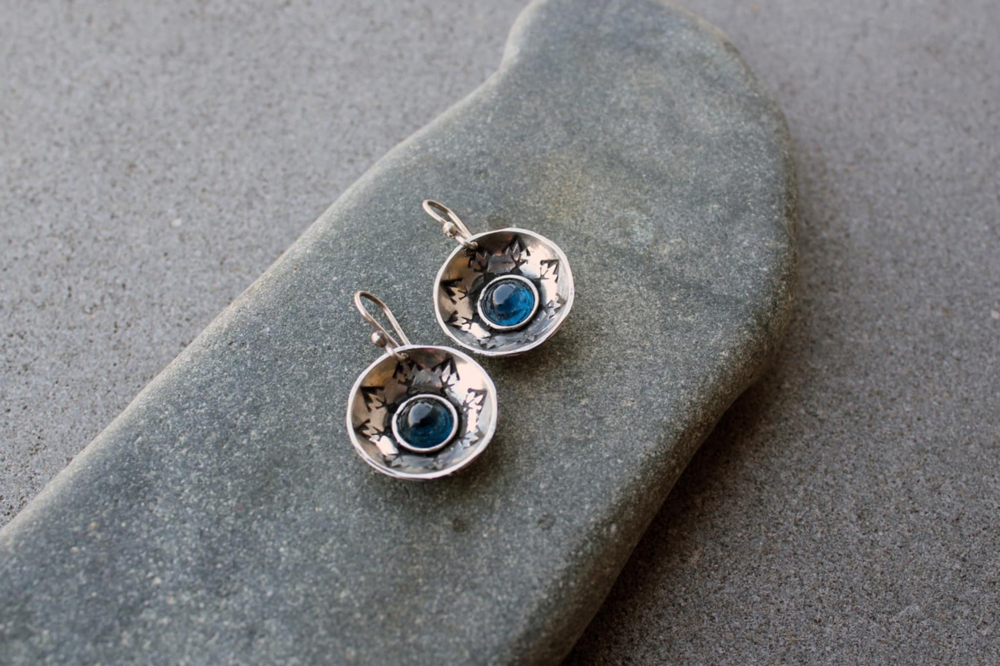 Handcrafted artisan Armenian silversmith sterling silver concave disc earrings featuring a central blue corundum cabochon, accented by stamped geometric patterns