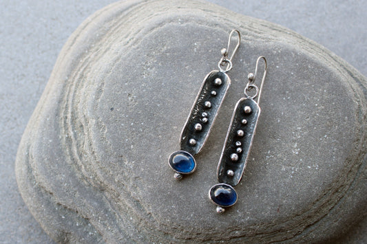 Handcrafted artisan Armenian reticulated sterling silver pod earrings featuring granulated textures and oval lab-grown blue corundum cabochons on classic ear wires