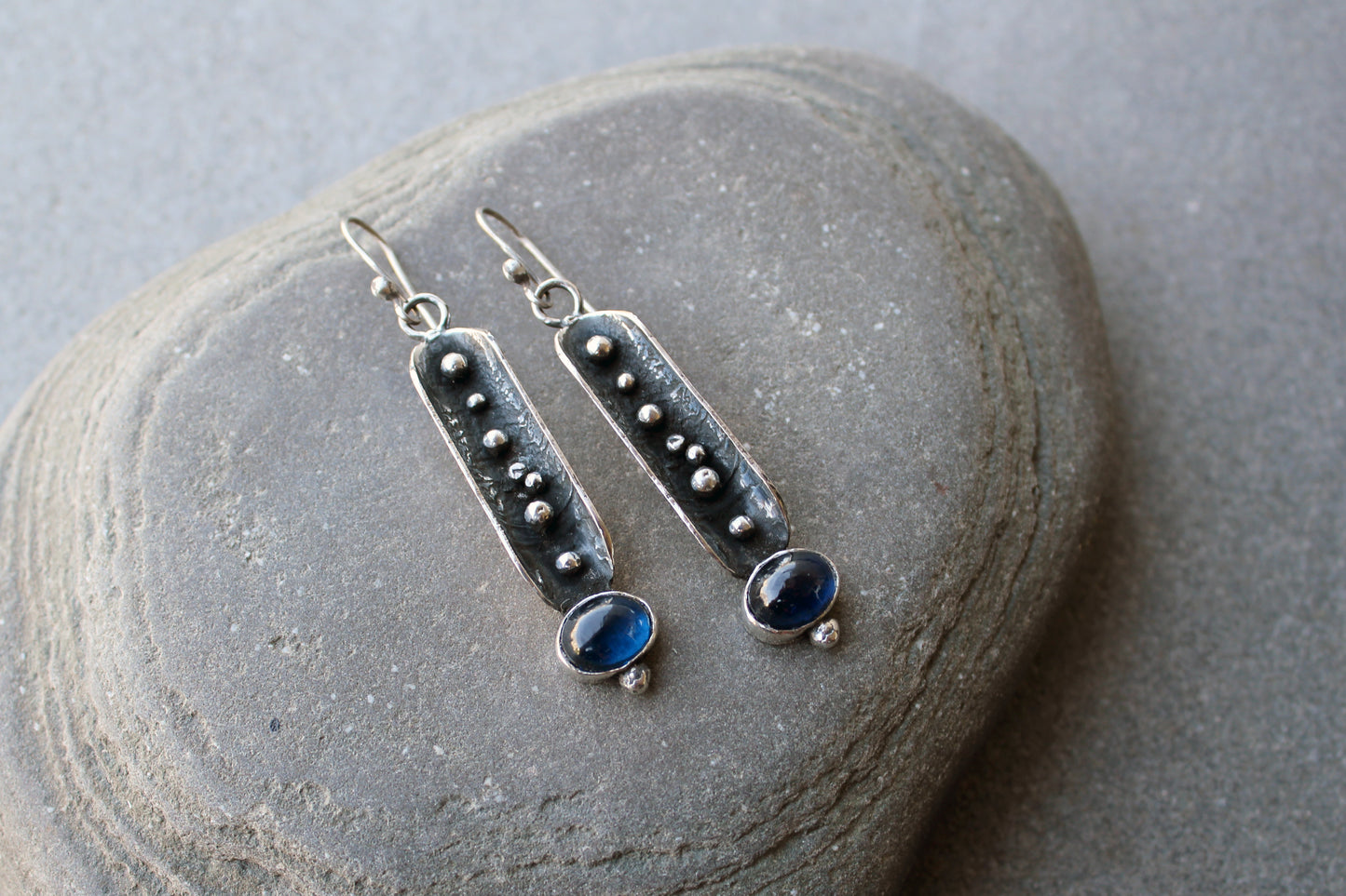 Handcrafted artisan Armenian reticulated sterling silver pod earrings featuring granulated textures and oval lab-grown blue corundum cabochons on classic ear wires