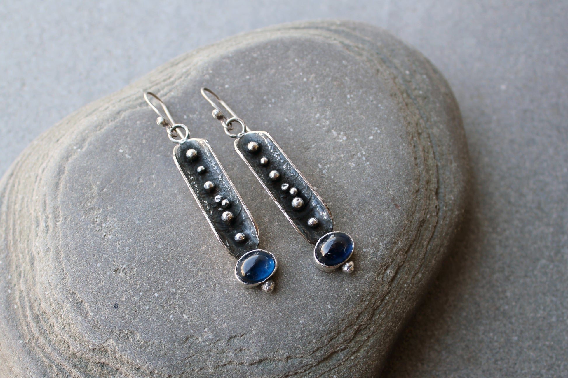 Handcrafted artisan Armenian reticulated sterling silver pod earrings featuring granulated textures and oval lab-grown blue corundum cabochons on classic ear wires