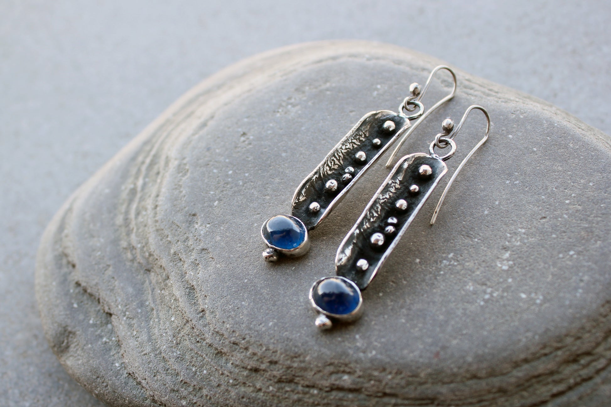 Handcrafted artisan Armenian reticulated sterling silver pod earrings featuring granulated textures and oval lab-grown blue corundum cabochons on classic ear wires