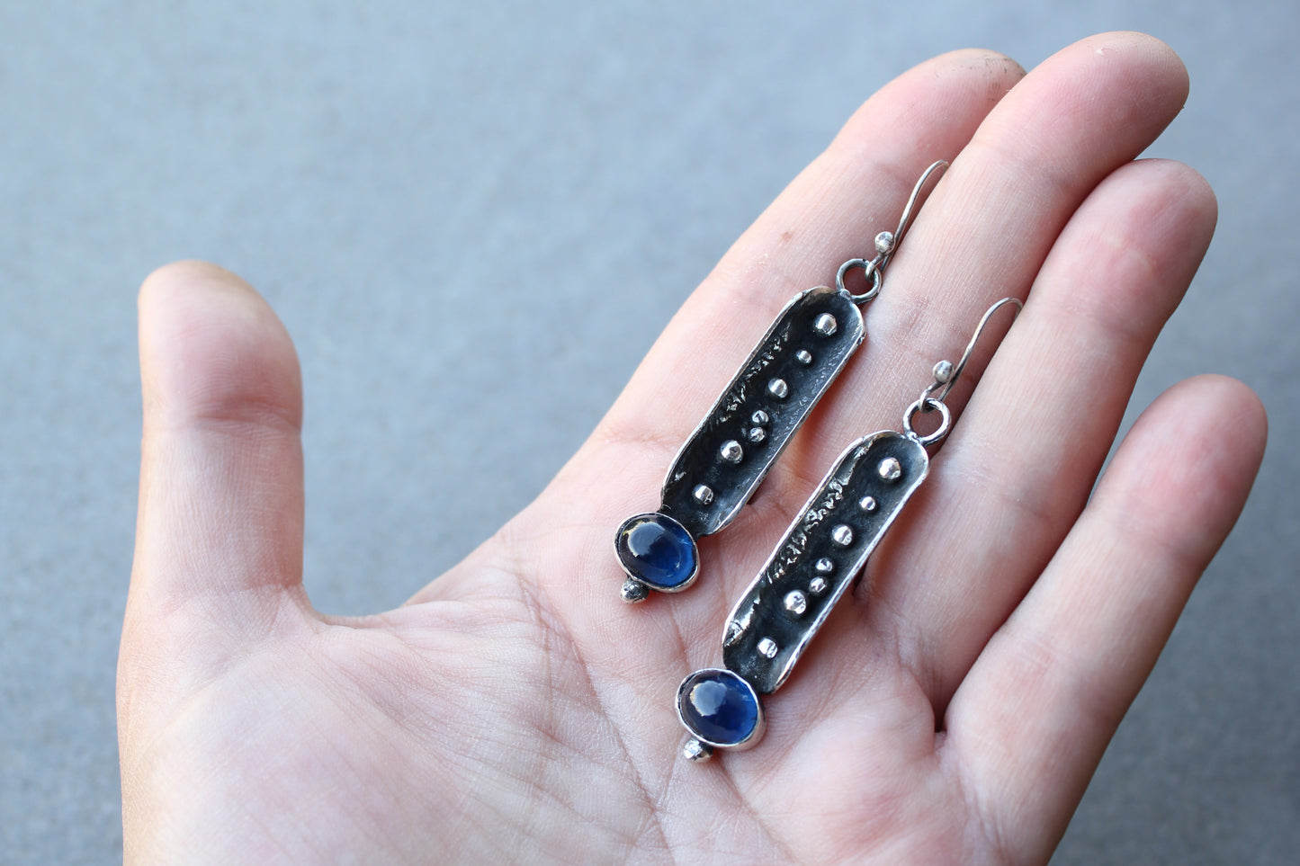Handcrafted artisan Armenian reticulated sterling silver pod earrings featuring granulated textures and oval lab-grown blue corundum cabochons on classic ear wires