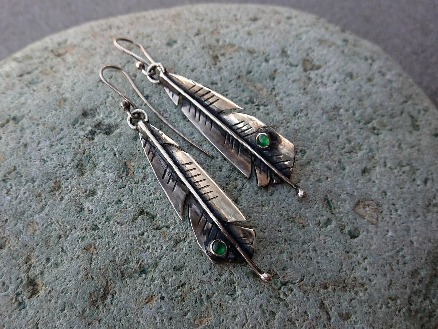 Handcrafted Armenian sterling silver artisan earrings shaped like detailed feathers, each set with small, vibrant round green onyx cabochon near the tip