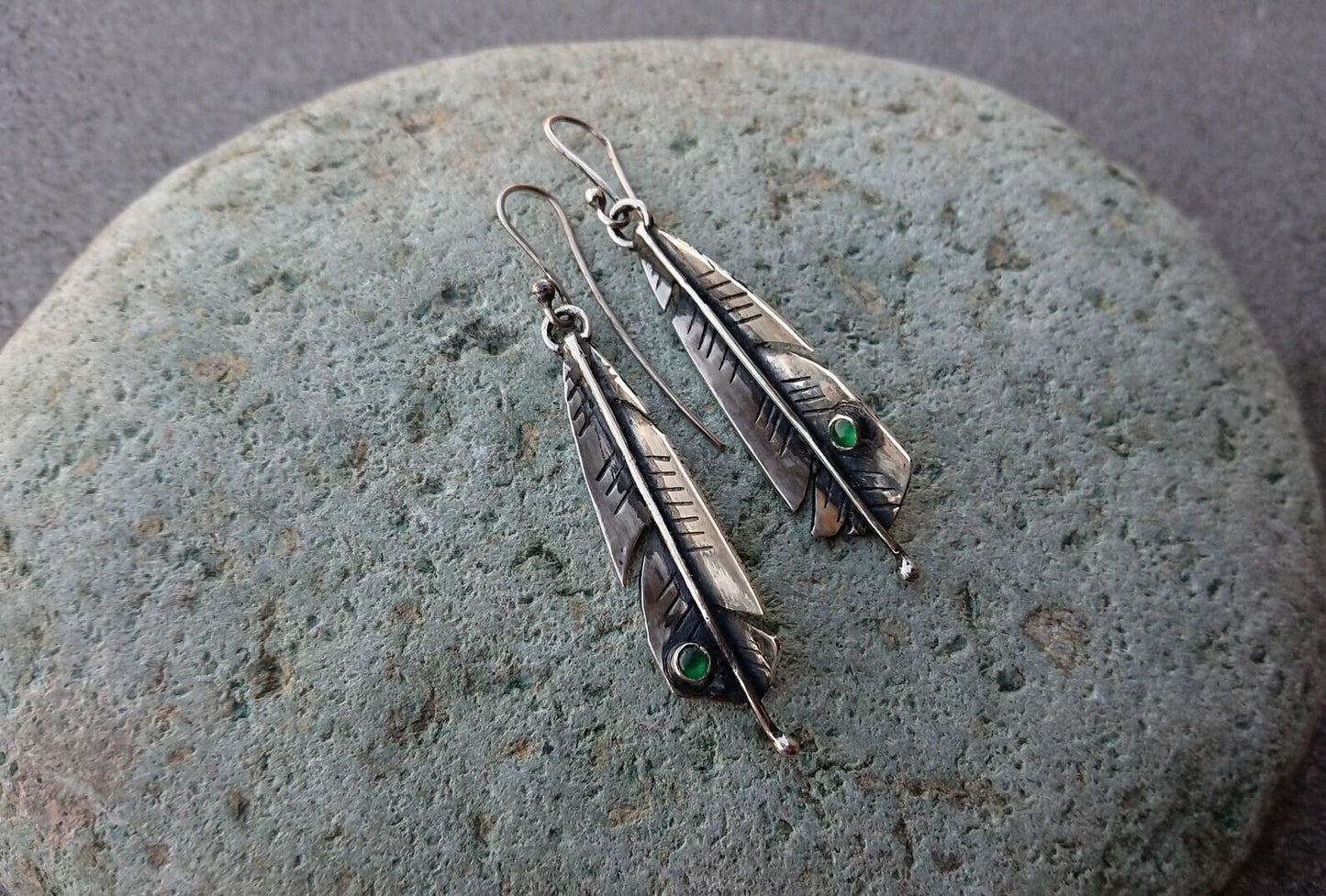Handcrafted Armenian sterling silver artisan earrings shaped like detailed feathers, each set with small, vibrant round green onyx cabochon near the tip