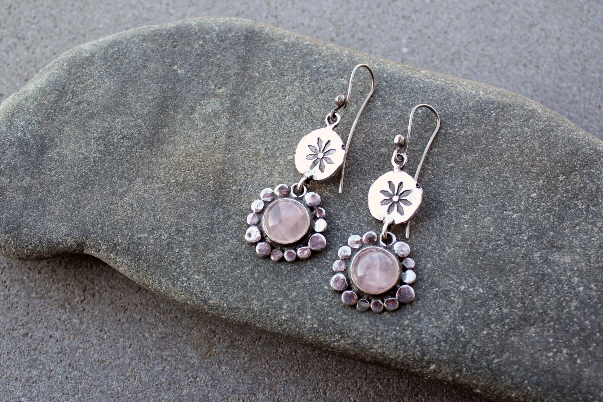 Handcrafted Armenian artisan drop earrings with round rose quartz cabochons. Features a hand stamped floral sunburst disc and a decorative beaded halo around the pink stones