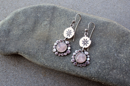 Handcrafted Armenian artisan drop earrings with round rose quartz cabochons. Features a hand stamped floral sunburst disc and a decorative beaded halo around the pink stones
