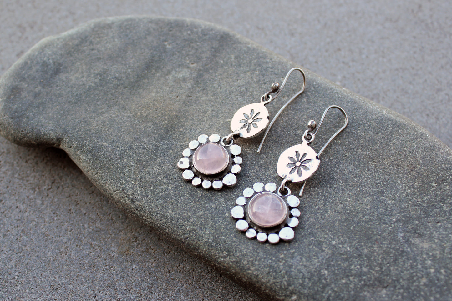 Handcrafted Armenian artisan drop earrings with round rose quartz cabochons. Features a hand stamped floral sunburst disc and a decorative beaded halo around the pink stones