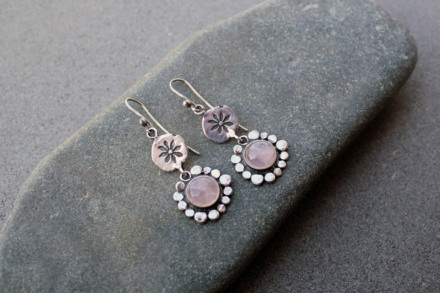 Handcrafted Armenian artisan drop earrings with round rose quartz cabochons. Features a hand stamped floral sunburst disc and a decorative beaded halo around the pink stones