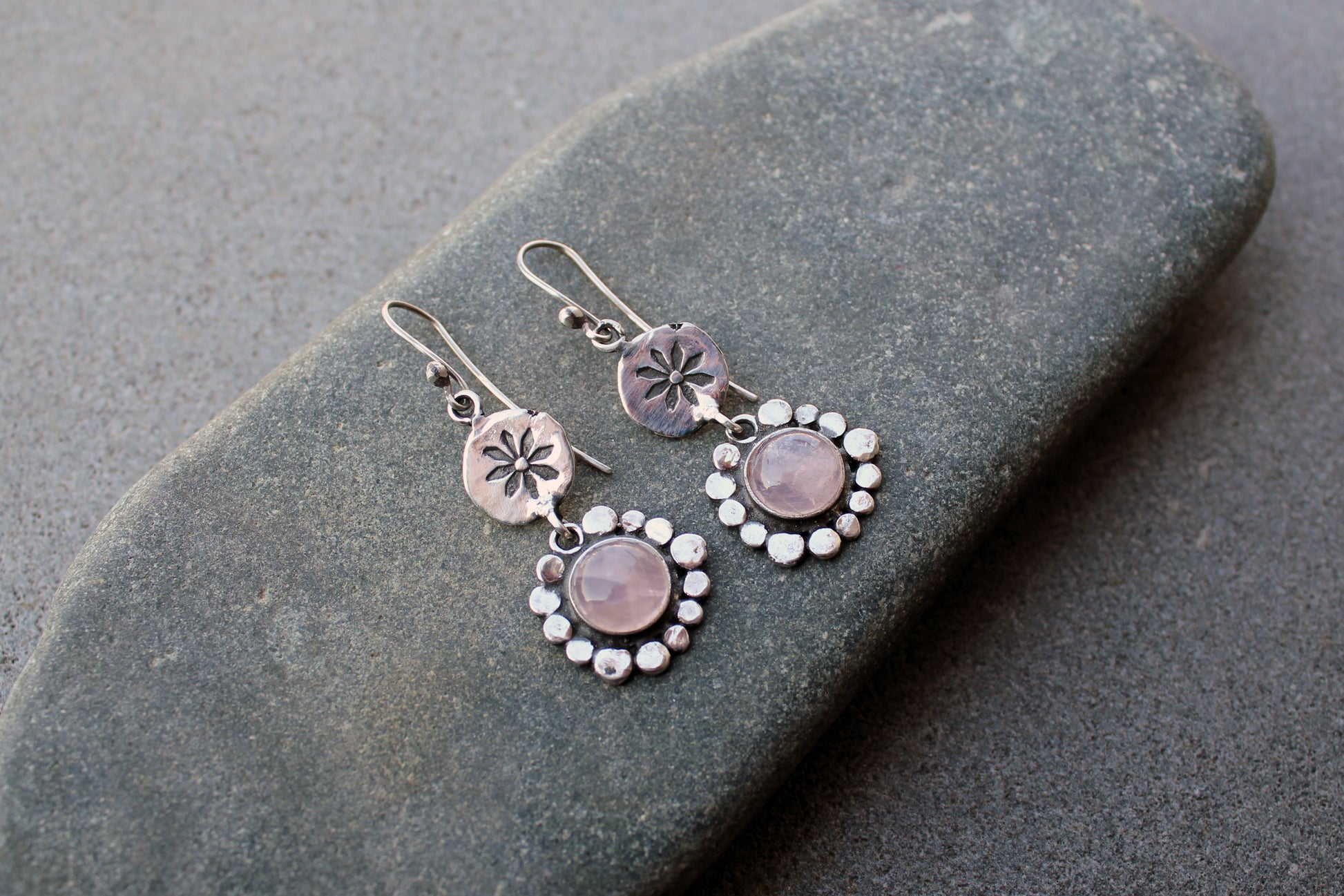 Handcrafted Armenian artisan drop earrings with round rose quartz cabochons. Features a hand stamped floral sunburst disc and a decorative beaded halo around the pink stones