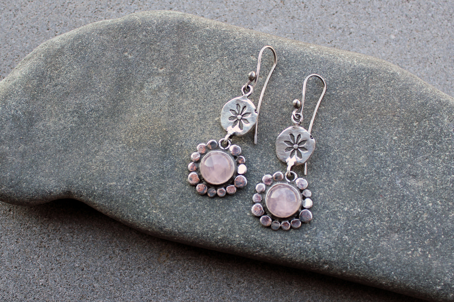 Handcrafted Armenian artisan drop earrings with round rose quartz cabochons. Features a hand stamped floral sunburst disc and a decorative beaded halo around the pink stones