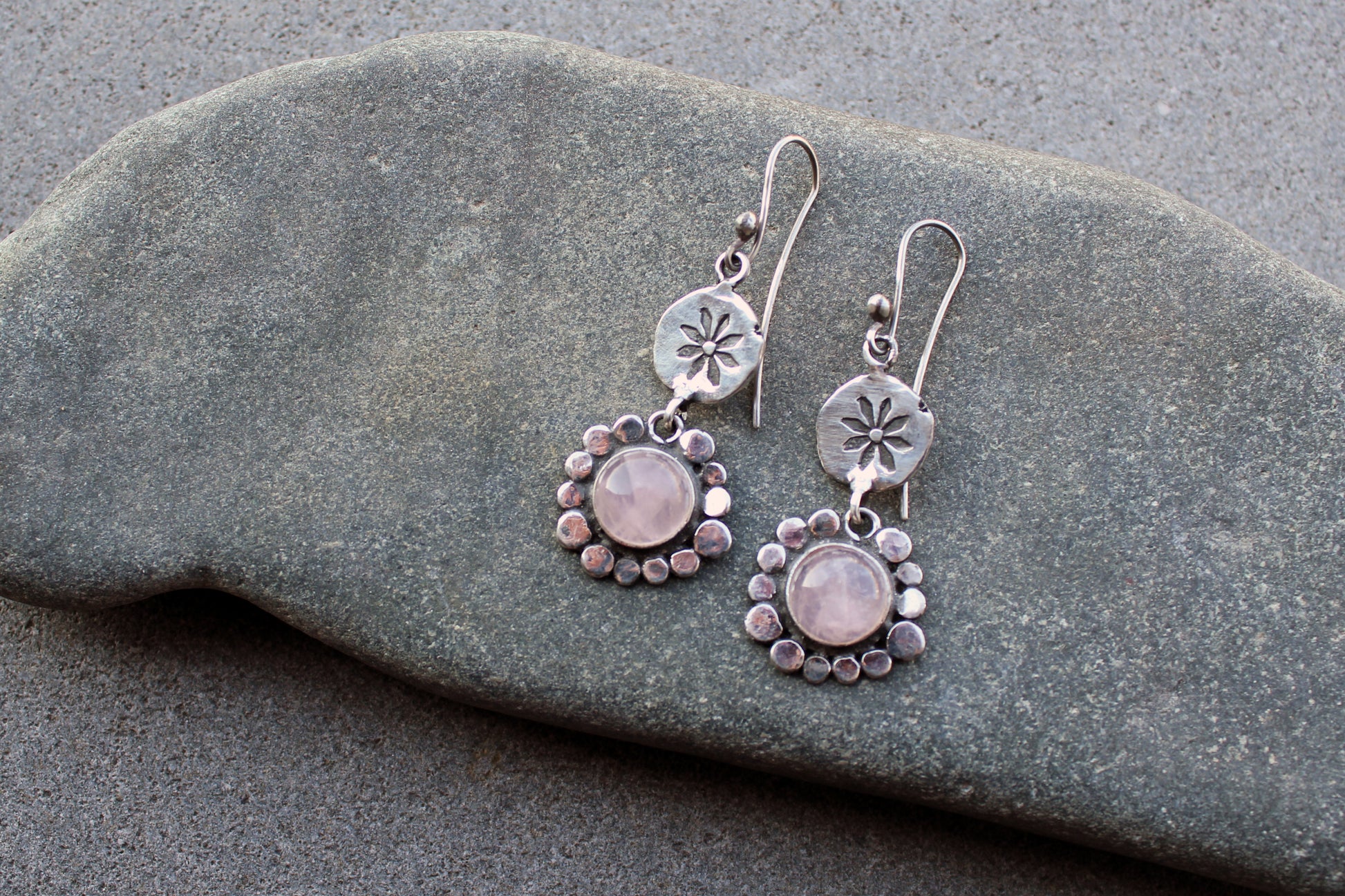 Handcrafted Armenian artisan drop earrings with round rose quartz cabochons. Features a hand stamped floral sunburst disc and a decorative beaded halo around the pink stones