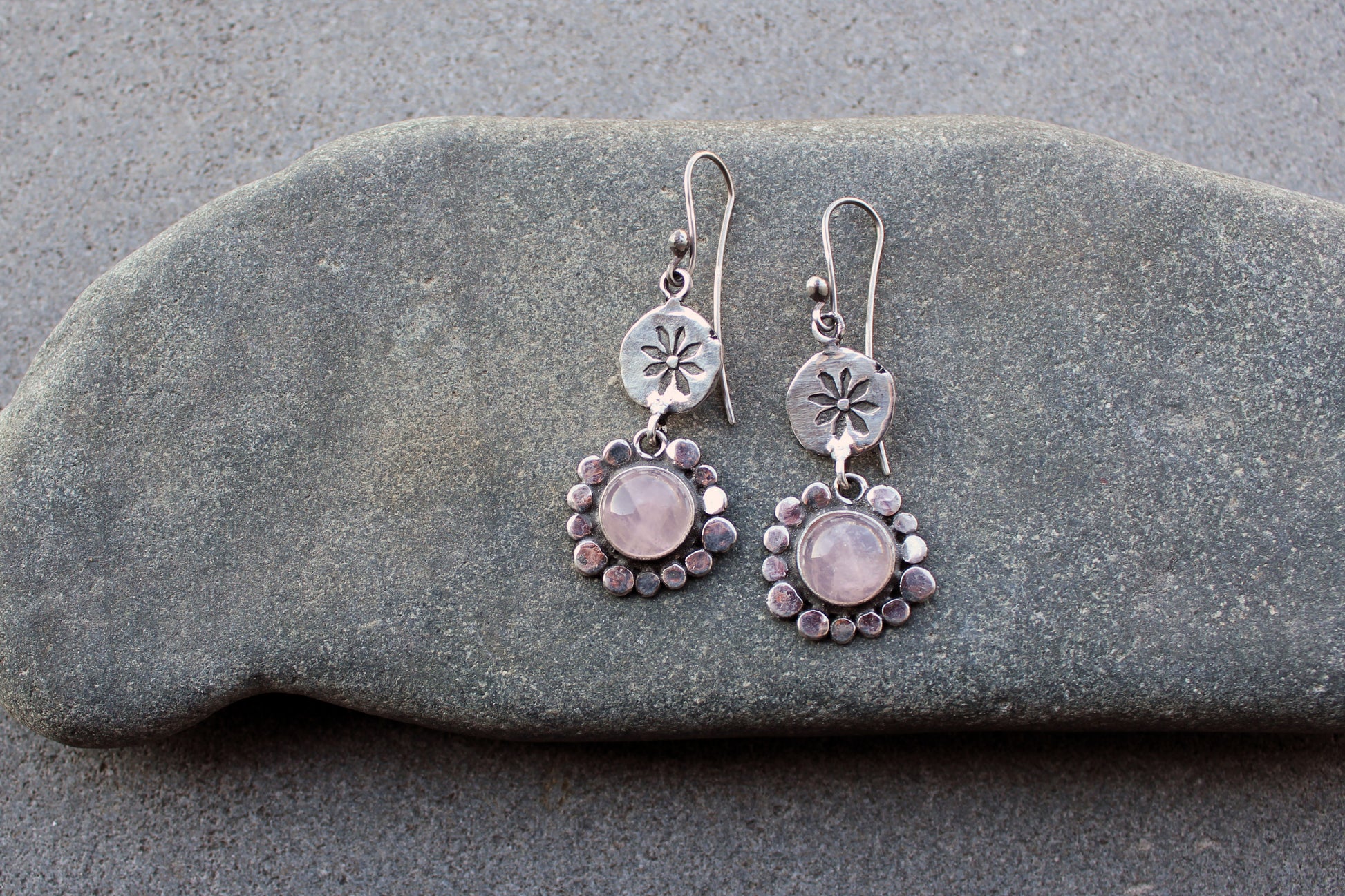 Handcrafted Armenian artisan drop earrings with round rose quartz cabochons. Features a hand stamped floral sunburst disc and a decorative beaded halo around the pink stones