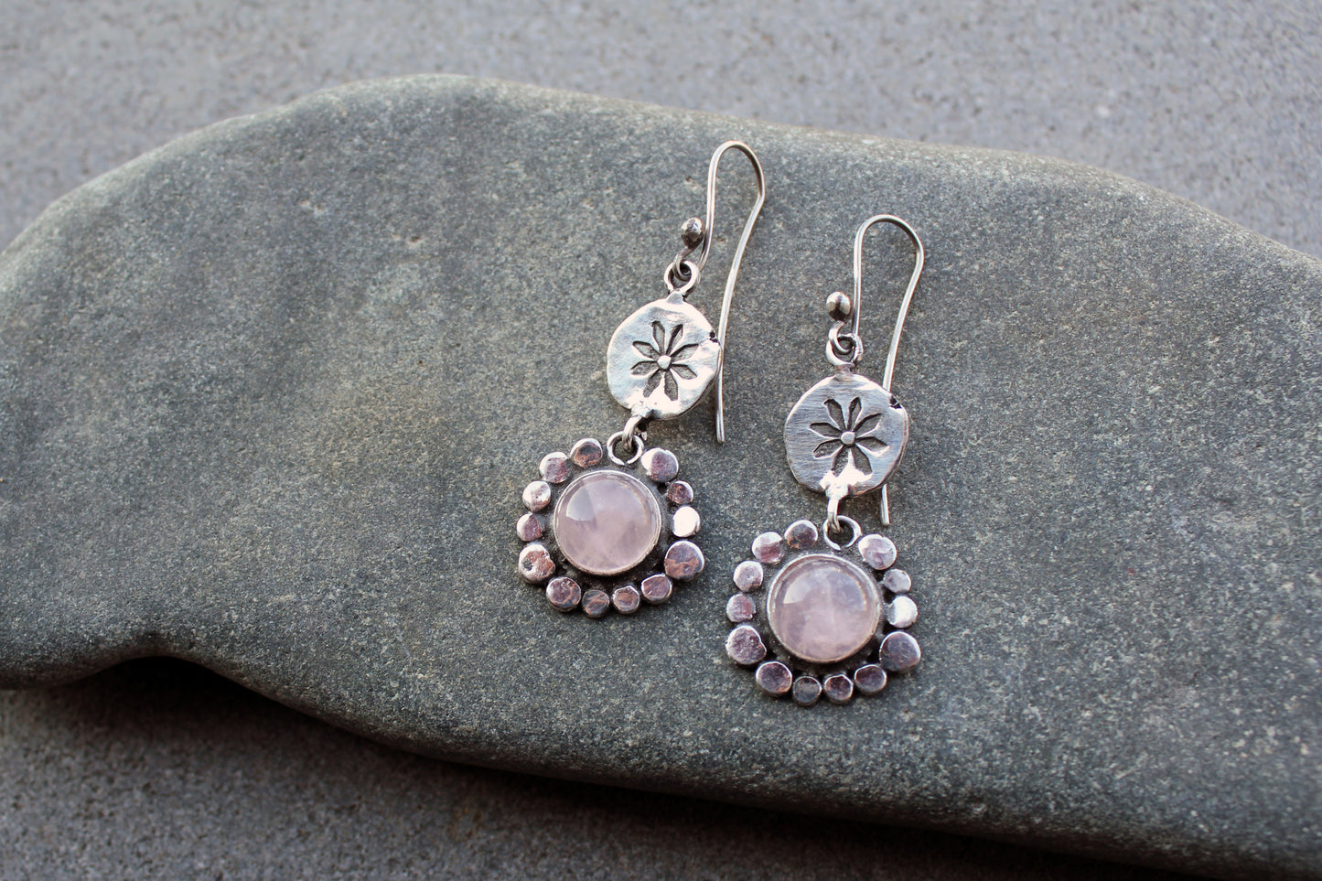 Handcrafted Armenian artisan drop earrings with round rose quartz cabochons. Features a hand stamped floral sunburst disc and a decorative beaded halo around the pink stones