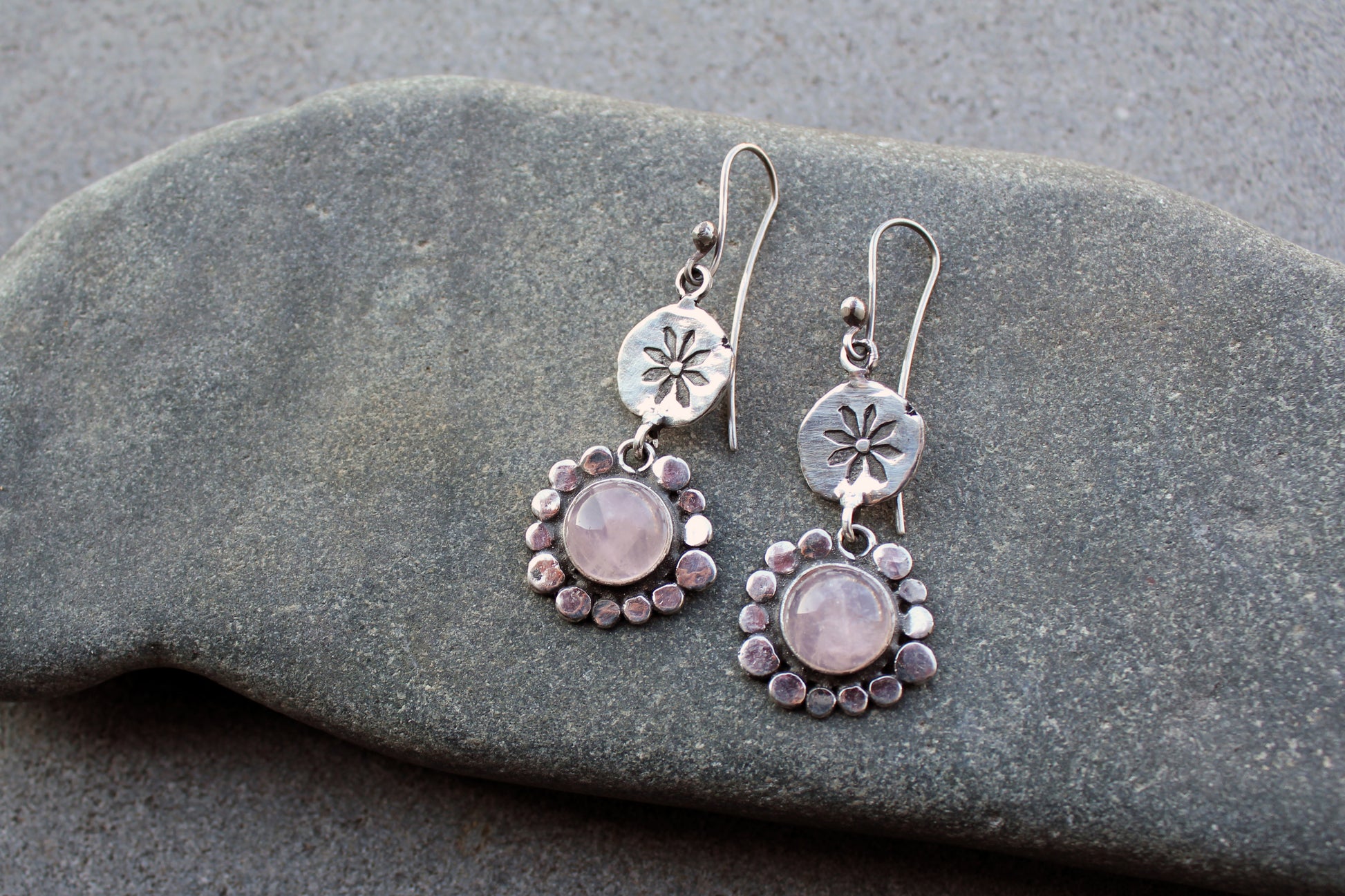 Handcrafted Armenian artisan drop earrings with round rose quartz cabochons. Features a hand stamped floral sunburst disc and a decorative beaded halo around the pink stones