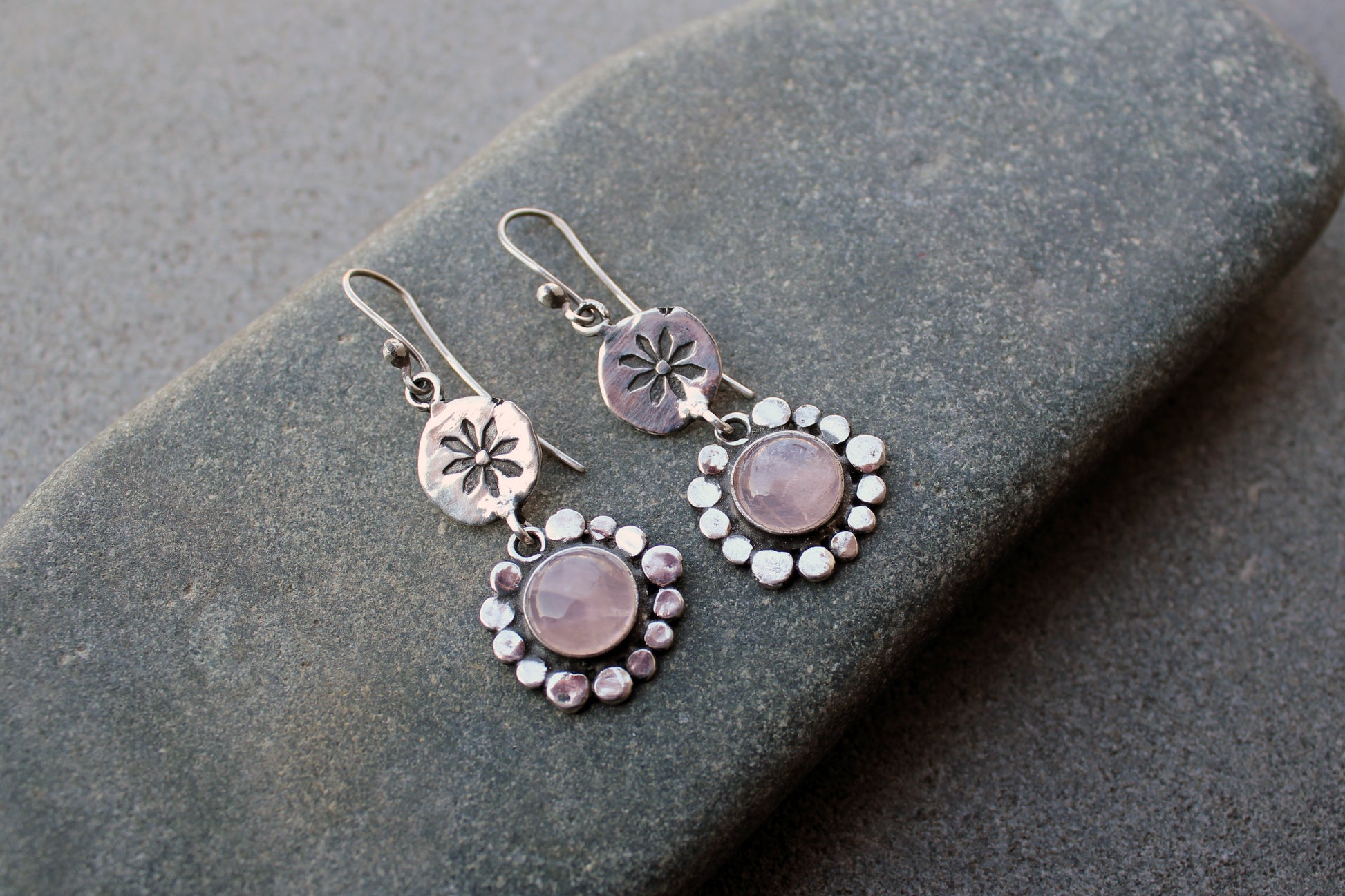 Handcrafted Armenian artisan drop earrings with round rose quartz cabochons. Features a hand stamped floral sunburst disc and a decorative beaded halo around the pink stones