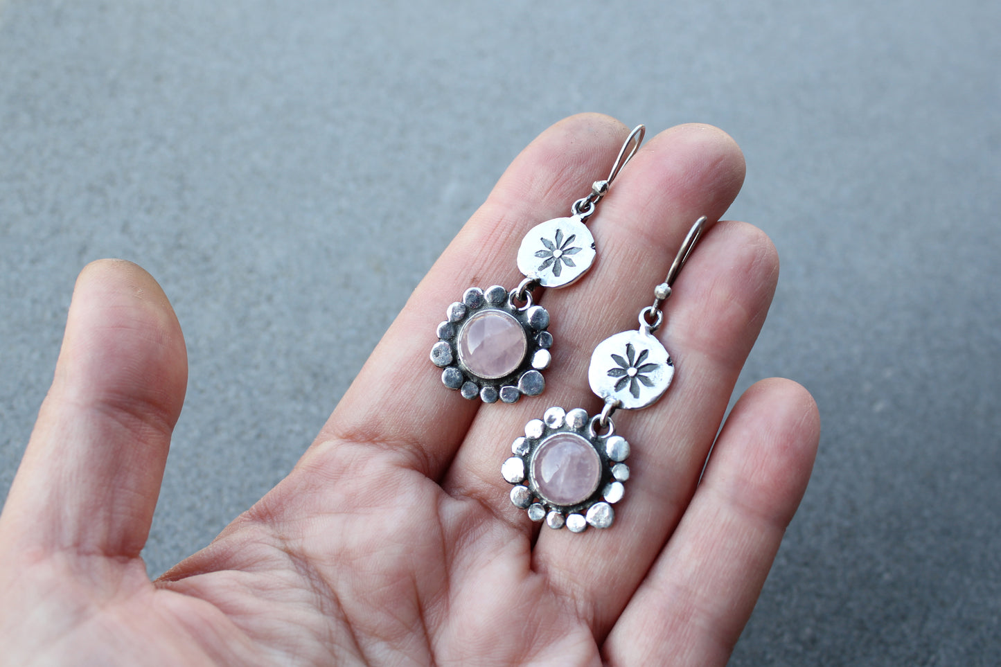 Handcrafted Armenian artisan drop earrings with round rose quartz cabochons. Features a hand stamped floral sunburst disc and a decorative beaded halo around the pink stones
