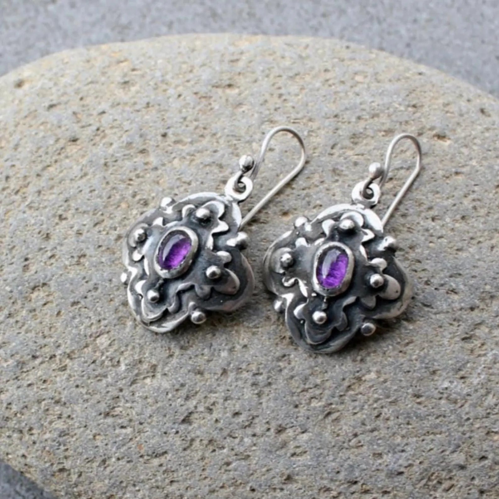 Handcrafted Armenian artisan silversmith sterling silver flower-shaped drop earrings with oval purple corundum centers, featuring oxidized details