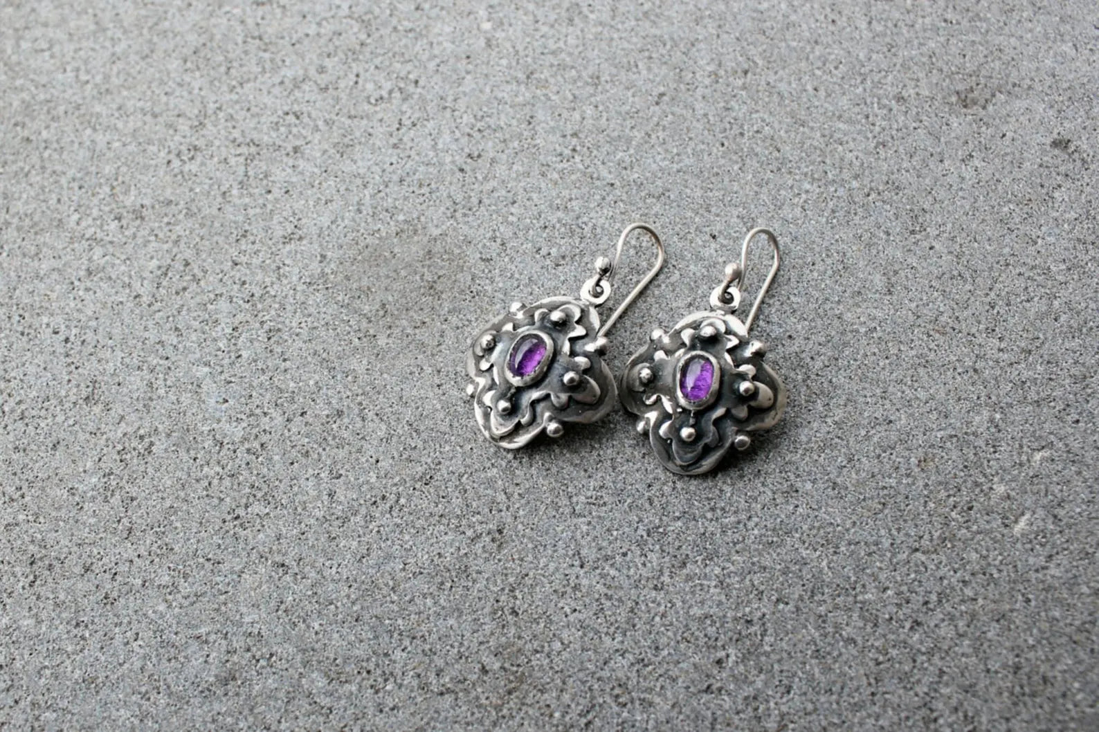 Handcrafted Armenian artisan silversmith sterling silver flower-shaped drop earrings with oval purple corundum centers, featuring oxidized details