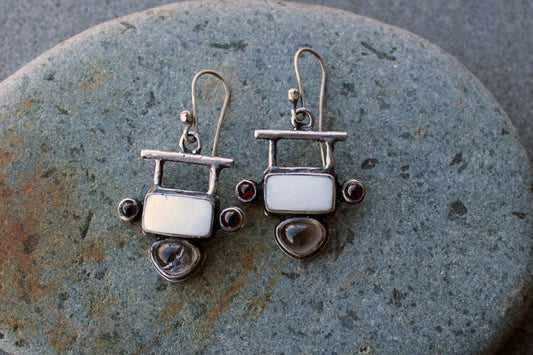 Handmade Armenian artisan sterling silver silversmith drop earrings featuring rectangular mother of pearl centers, accented by small round red garnets on the sides and teardrop-shaped grey obsidian at the base