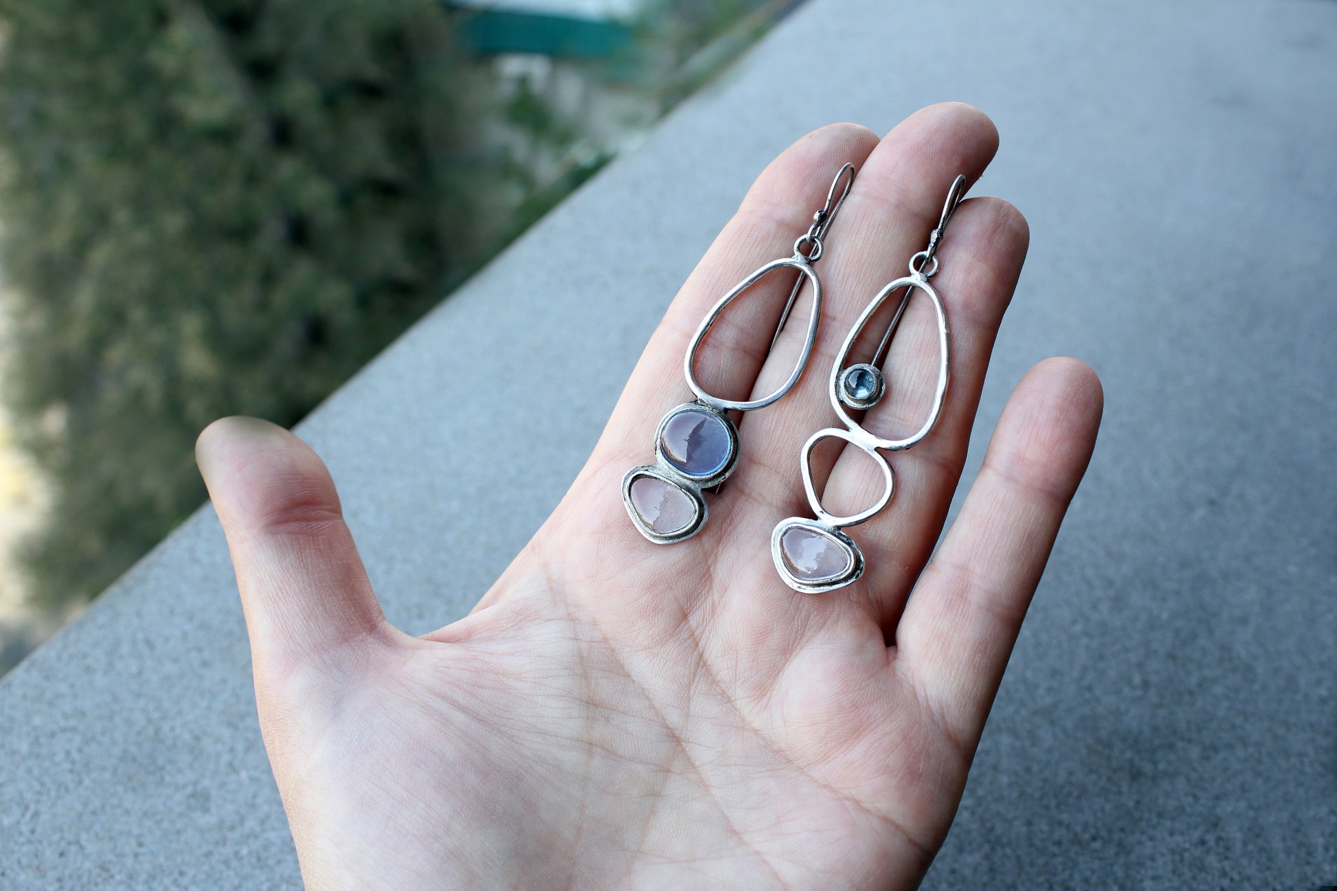 Handcrafted Armenian lightweight silver earrings featuring organic-shaped open frames and polished blue and transparent stones, handcrafted by a jewelry artisan