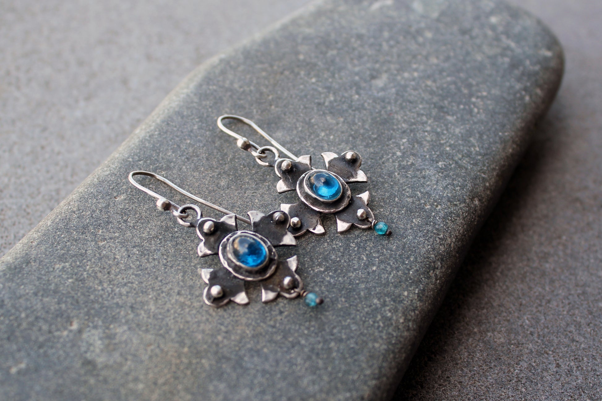 Armenian artisan vintage style sterling silver silversmith earrings featuring oval blue corundum gemstones set in a decorative floral frame
