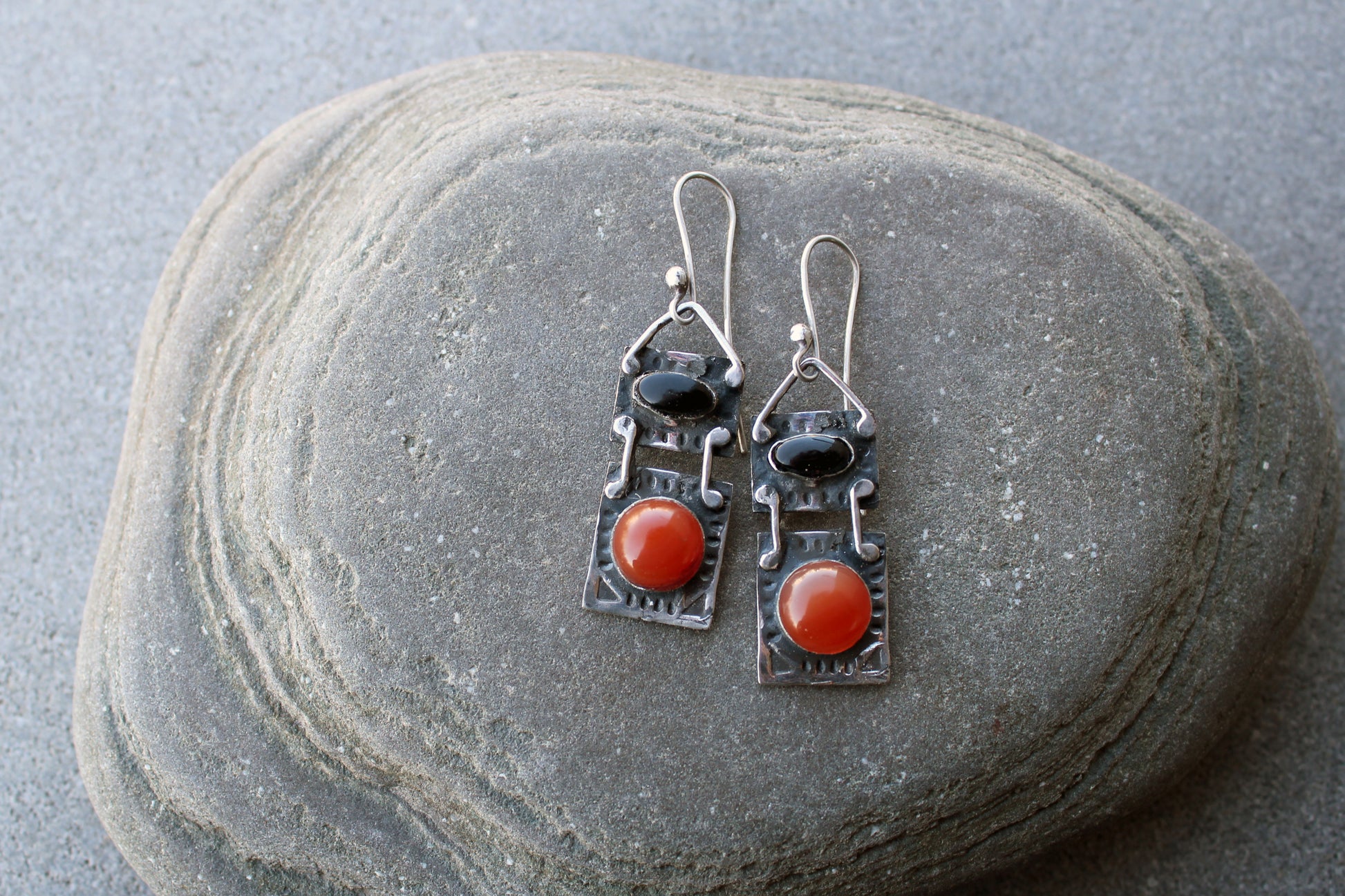 Handcrafted artisan drop earrings featuring oval black onyx and round carnelian  cabochons, set in oxidized sterling silver with tribal-style geometric engravings