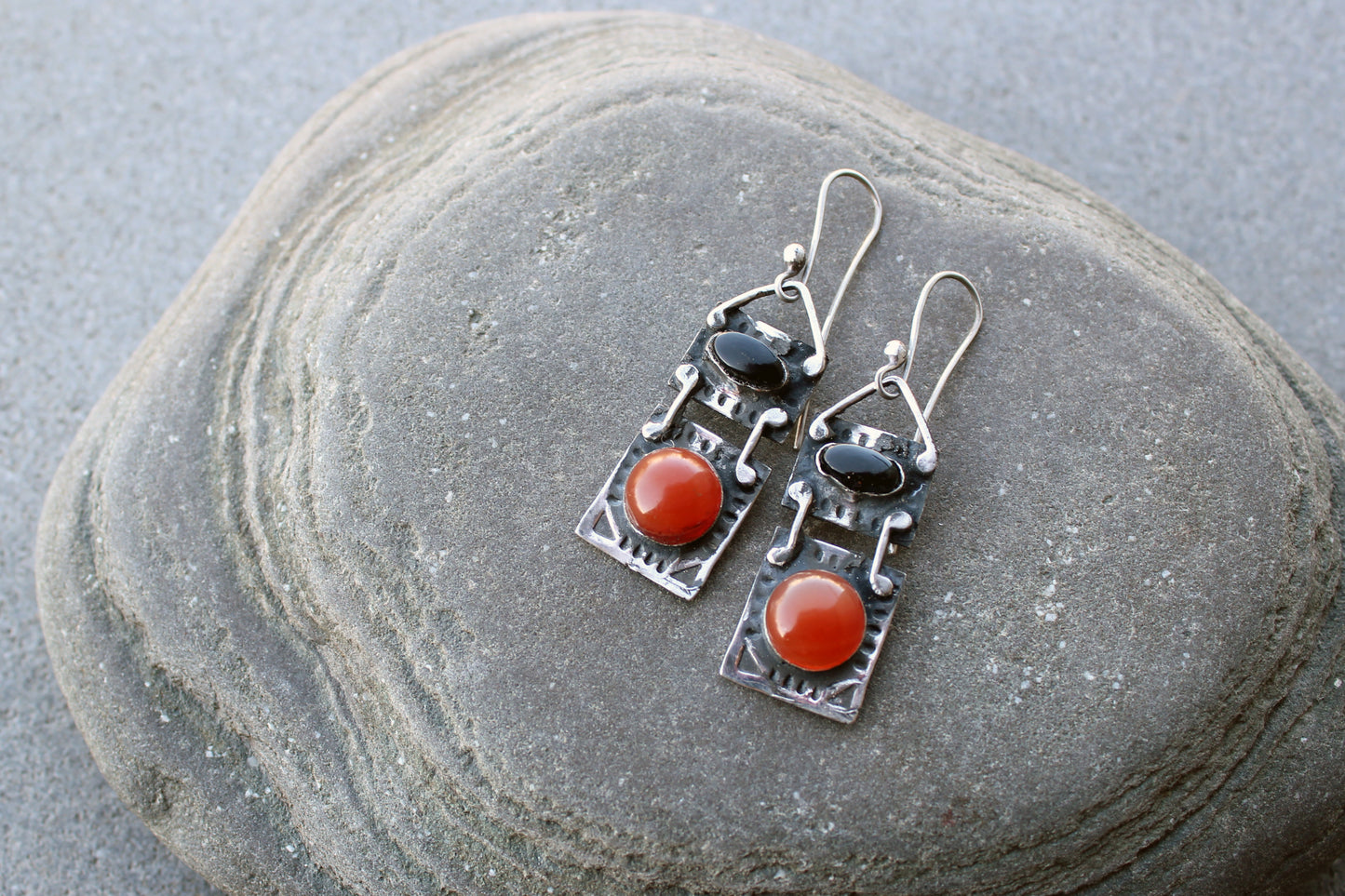 Handcrafted artisan drop earrings featuring oval black onyx and round carnelian  cabochons, set in oxidized sterling silver with tribal-style geometric engravings
