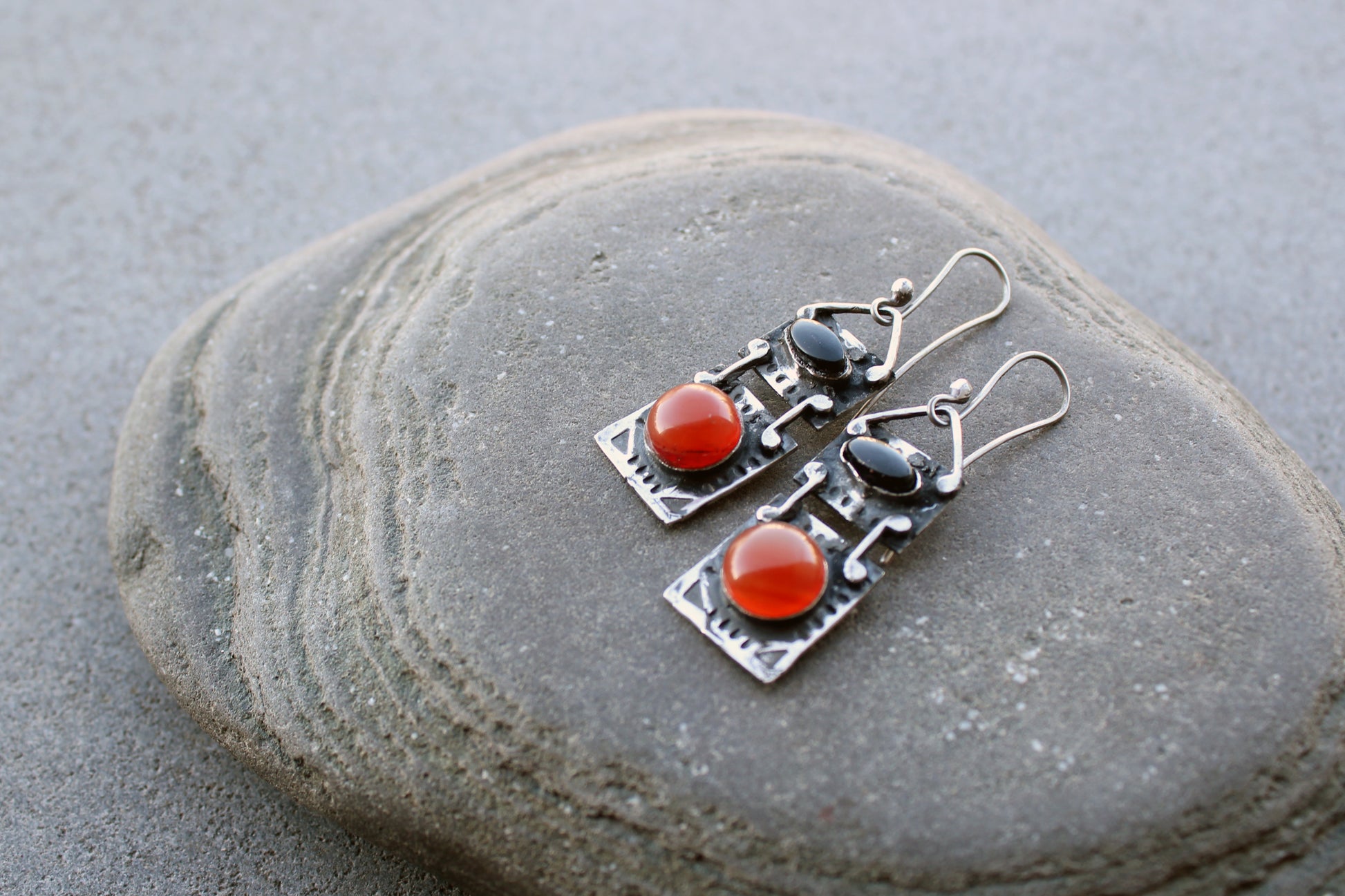 Handcrafted artisan drop earrings featuring oval black onyx and round carnelian  cabochons, set in oxidized sterling silver with tribal-style geometric engravings