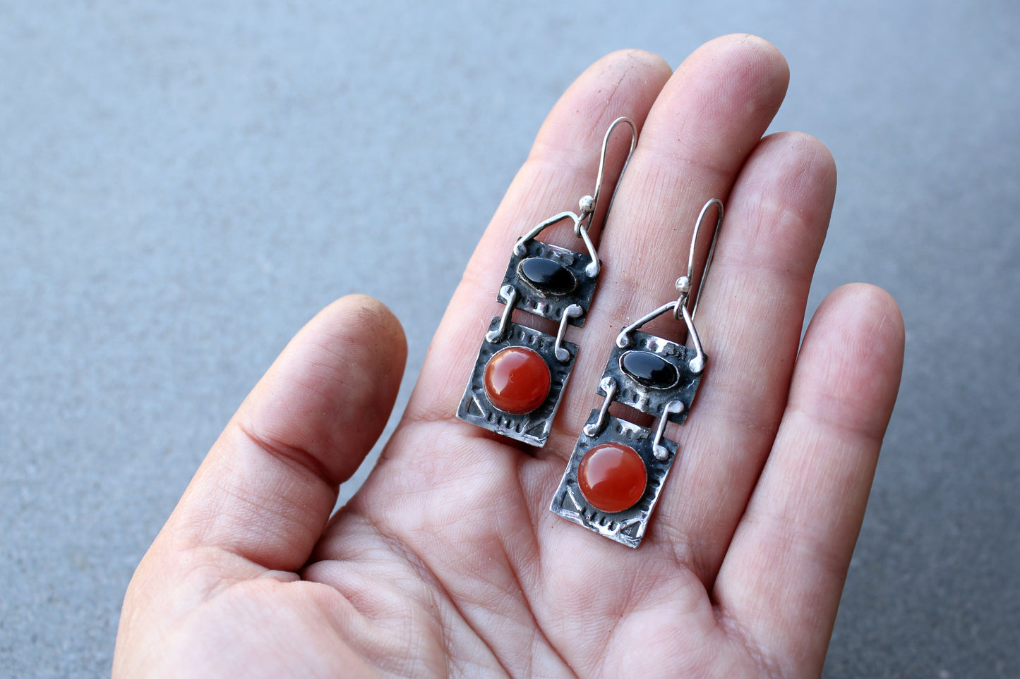 Handcrafted artisan drop earrings featuring oval black onyx and round carnelian  cabochons, set in oxidized sterling silver with tribal-style geometric engravings